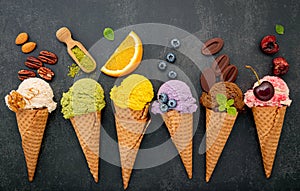 Various of ice cream flavor in cones blueberry ,green tea ,pistachio ,almond ,orange and cherry setup on dark stone background .