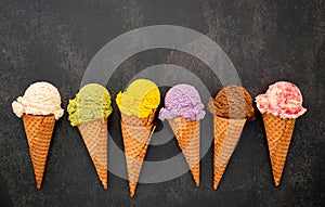 Various of ice cream flavor in cones blueberry ,green tea ,pistachio ,almond ,orange and cherry setup on dark stone background .