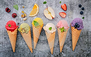 Various of ice cream flavor in cones blueberry ,green tea ,pistachio ,almond ,orange and cherry setup on dark stone background .