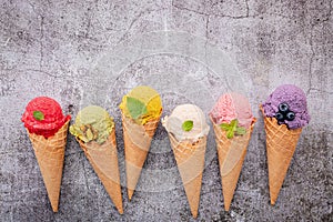 Various of ice cream flavor in cones blueberry ,green tea ,pistachio ,almond ,orange and cherry setup on dark stone background .