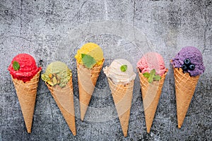 Various of ice cream flavor in cones blueberry ,green tea ,pistachio ,almond ,orange and cherry setup on dark stone background .