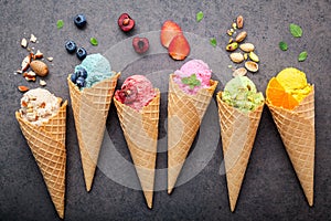 Various of ice cream flavor in cones blueberry ,strawberry ,pistachio ,almond ,orange and cherry setup on dark stone background .