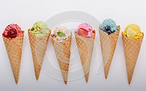 Various of ice cream flavor in cones blueberry ,strawberry ,pistachio ,almond ,orange and cherry setup on white wooden background