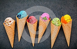 Various of ice cream flavor in cones blueberry ,strawberry ,pistachio ,almond ,orange and cherry setup on dark stone background .