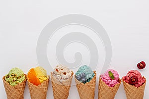 Various of ice cream flavor in cones blueberry ,strawberry ,pistachio ,almond ,orange and cherry setup on white wooden background