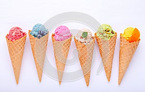 Various of ice cream flavor in cones blueberry ,strawberry ,pistachio ,almond ,orange and cherry setup on white wooden background