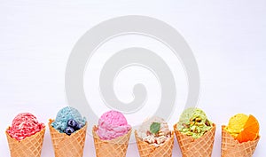 Various of ice cream flavor in cones blueberry ,strawberry ,pistachio ,almond ,orange and cherry setup on white wooden background