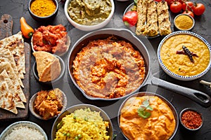 Various Indian dishes on a table. Spicy chicken Tikka Masala in iron pan