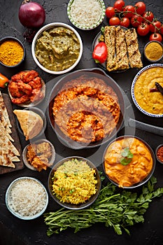 Various Indian dishes on a table. Spicy chicken Tikka Masala in iron pan