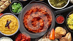 Various Indian dishes on a table. Spicy chicken Tikka Masala in iron pan