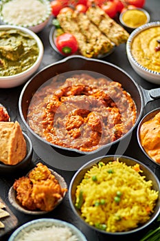 Various Indian dishes on a table. Spicy chicken Tikka Masala in iron pan photo