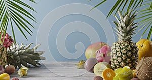 Various juicy exotic fruits - lychee, pineapple and carambola on a gray wooden table on a blue. Dolly out motion, 4K UHD