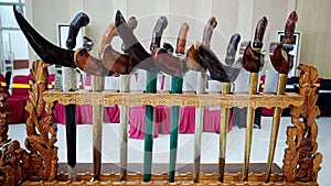 Various keris or traditional Indonesian weapons with unique wood carvings are arranged in place of weapons