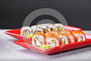 Various kind of sushi food served in red plated over black background. Traditional Japanese cuisine