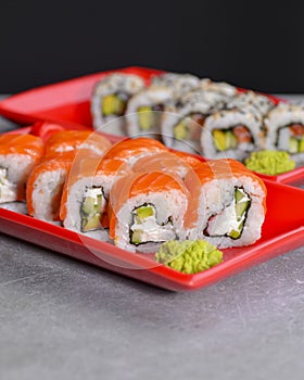 Various kind of sushi food served in red plated over black background. Traditional Japanese cuisine