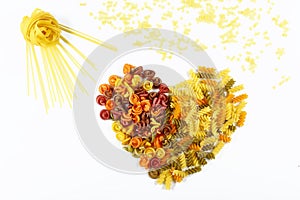 Various kinds of colored raw Italian pasta on a white background, top view, in the form of sun with rays, valentine heart from foo