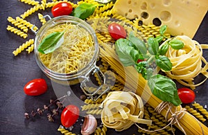 Various kinds of pasta ingredients with basil, cherry tomato, garlic, pepper and cheese