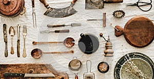 Various kitchen utensils and tablewear over linen tablecloth, wide composition photo