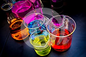 Various laboratory beakers and cylinders filled with colorful liquids o