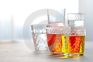 Various lemonades in glass faceted glasses on a gray table.