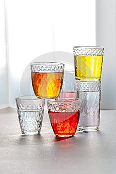 Various lemonades in glass faceted glasses on a gray table