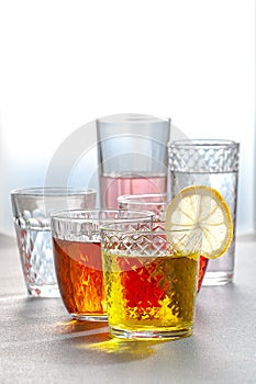 Various lemonades in glass faceted glasses on a gray table. Photo with a gradient background