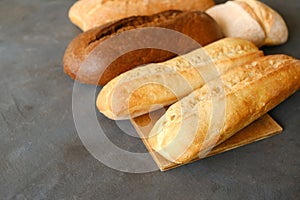 Various loaves of bread. Baked baguette bread and brown loaf of bread on grey table.