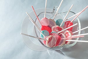 Various lollipops in a transparente bowl with light blue background