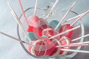 Various lollipops in a transparente bowl with light blue background photo