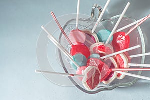 Various lollipops in a transparente bowl with light blue background photo