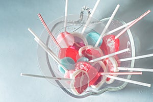 Various lollipops in a transparente bowl with light blue background photo