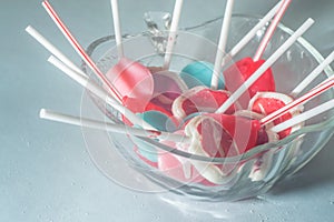 Various lollipops in a transparente bowl with light blue background photo