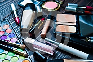 Various makeup products on dark background. Cosmetics make up artist objects: lipstick, eye shadows, eyeliner, concealer