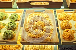 Various mix of uncooked pasta in on wooden tray in the shop window. Different kind of dry macaroni in round form. Italian foods