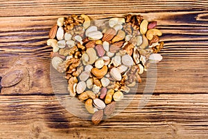 Various nuts almond, cashew, hazelnut, pistachio, walnut in shape of heart on a wooden table. Vegetarian meal. Healthy eating