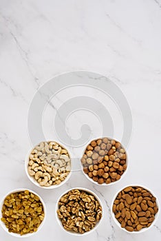 Various nuts and dried fruits in white bowls