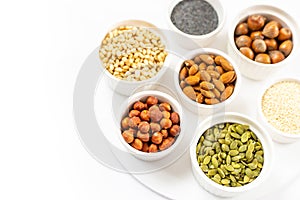 Various Nuts and Seeds on White Background in the Bowls with Free Space for Text