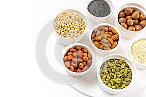 Various Nuts and Seeds on White Background in the Bowls with Free Space for Text