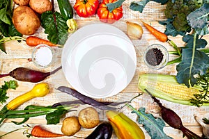 Various organic vegetables ingredients around empty plate