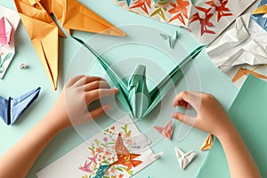 various origami papers and a halffinished paper crane with small hands at work