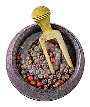 Various peppercorns in bowl with scoop isolated above