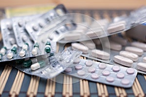 Various pills and capsules in blister packagings piled up on a glass table