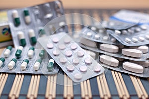 Various pills and capsules in blister packagings piled up on a glass table