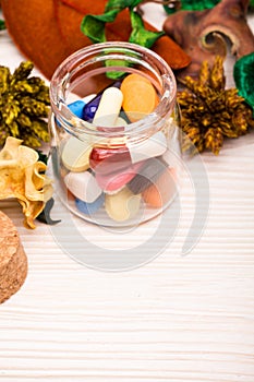 Various pills and capsules in glass container with green