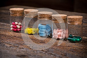 Various pills and capsules in glass containers with caps