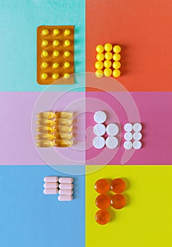 Various pills and capsules on multicolor background, supplements