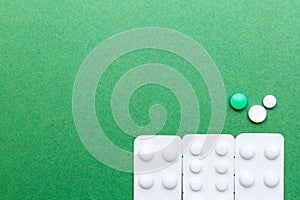 Various pills on the green background with copy space.