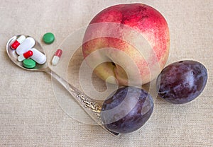 Various pills, spoon and thermometer. Fruits contain a lot of vi