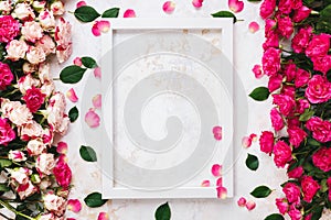 Various  pink and red roses directed at each other and empty white wooden frame photo