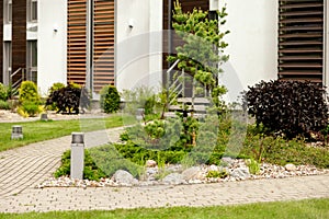 Various plants and stones in front of modern house, front yard. Landscape design. Beautiful garden. Modern urban living